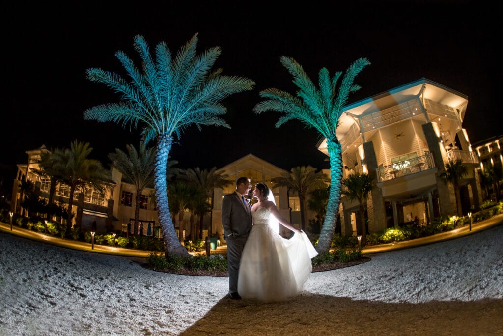 bride and groom on sand at night with palm trees and lights behind them at margaritaville resort orlando wedding venue